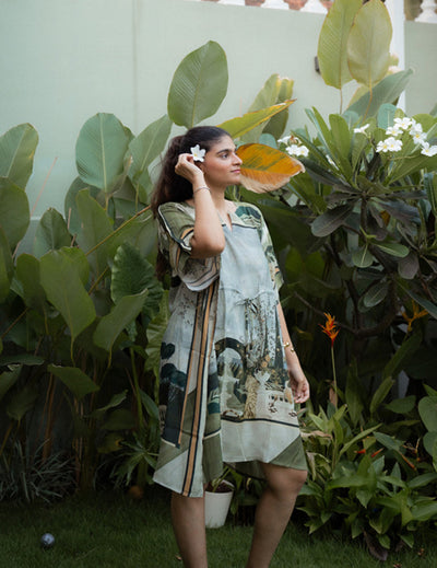 Woman in a patterned dress standing among green plants